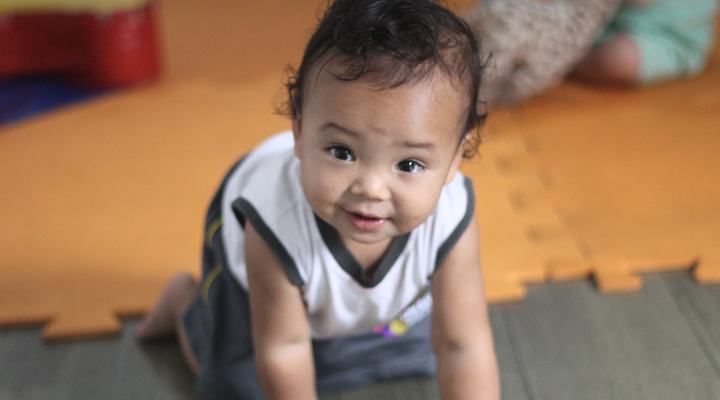 Bebê do berçário do Colégio Crer&Ser engatinhando e sorrindo