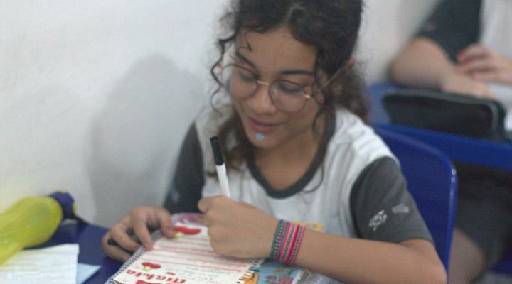 Aluna do Colégio Crer&Ser estudando com material bilíngue em sala de aula