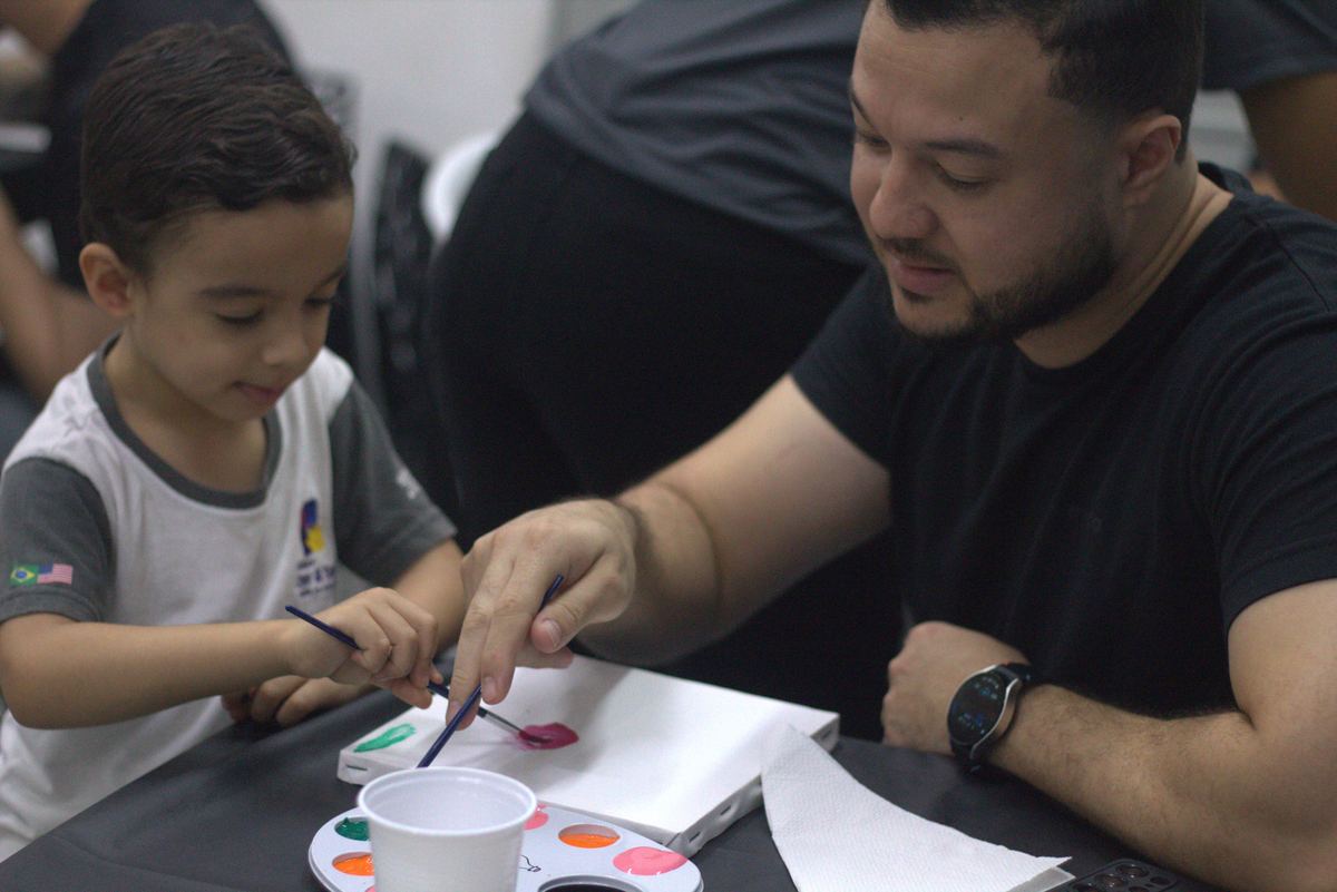 Pai e filho pintando juntos em evento de família no Colégio Crer&Ser