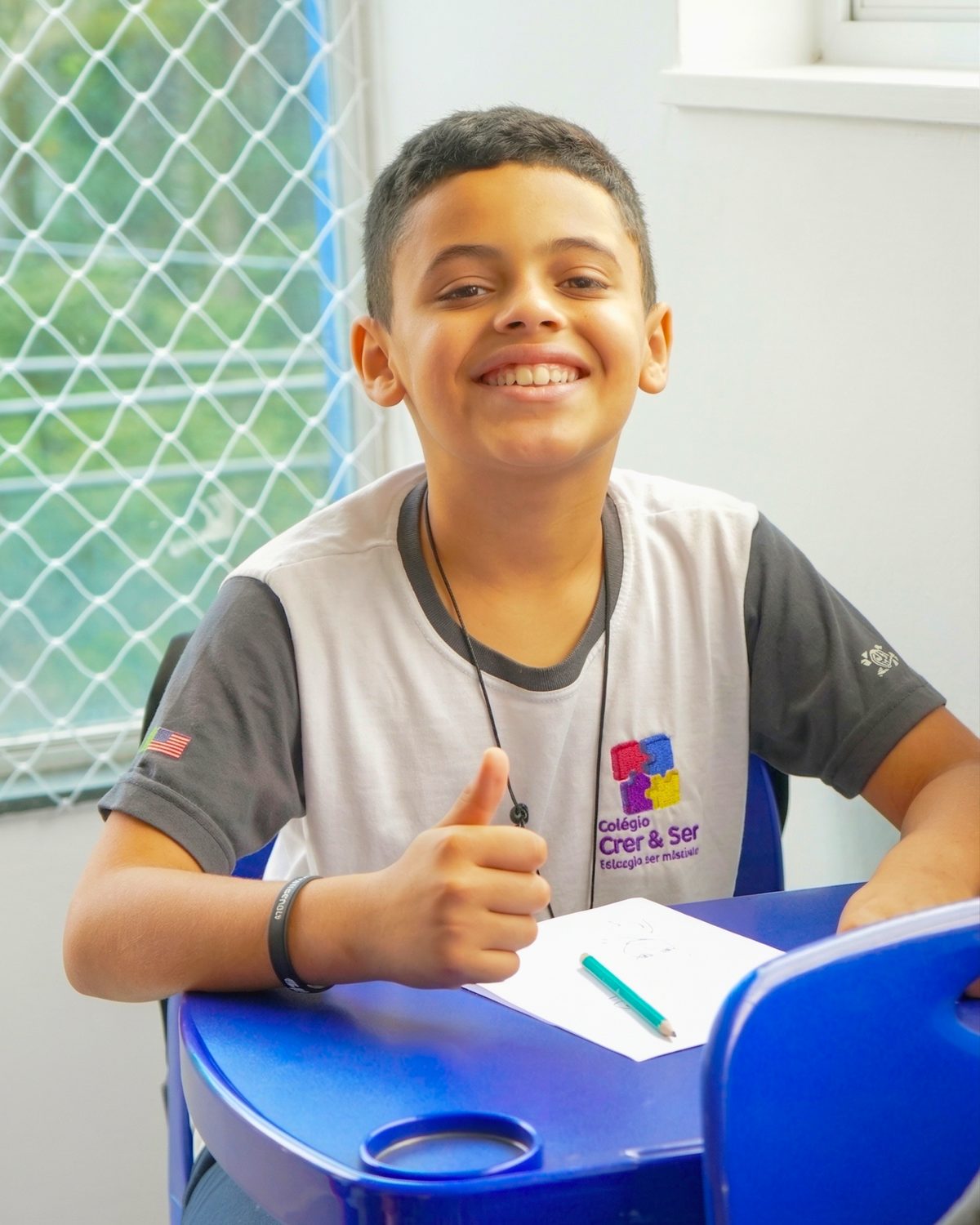 Aluno do Ensino Fundamental do Colégio Crer&Ser sorrindo em sala de aula